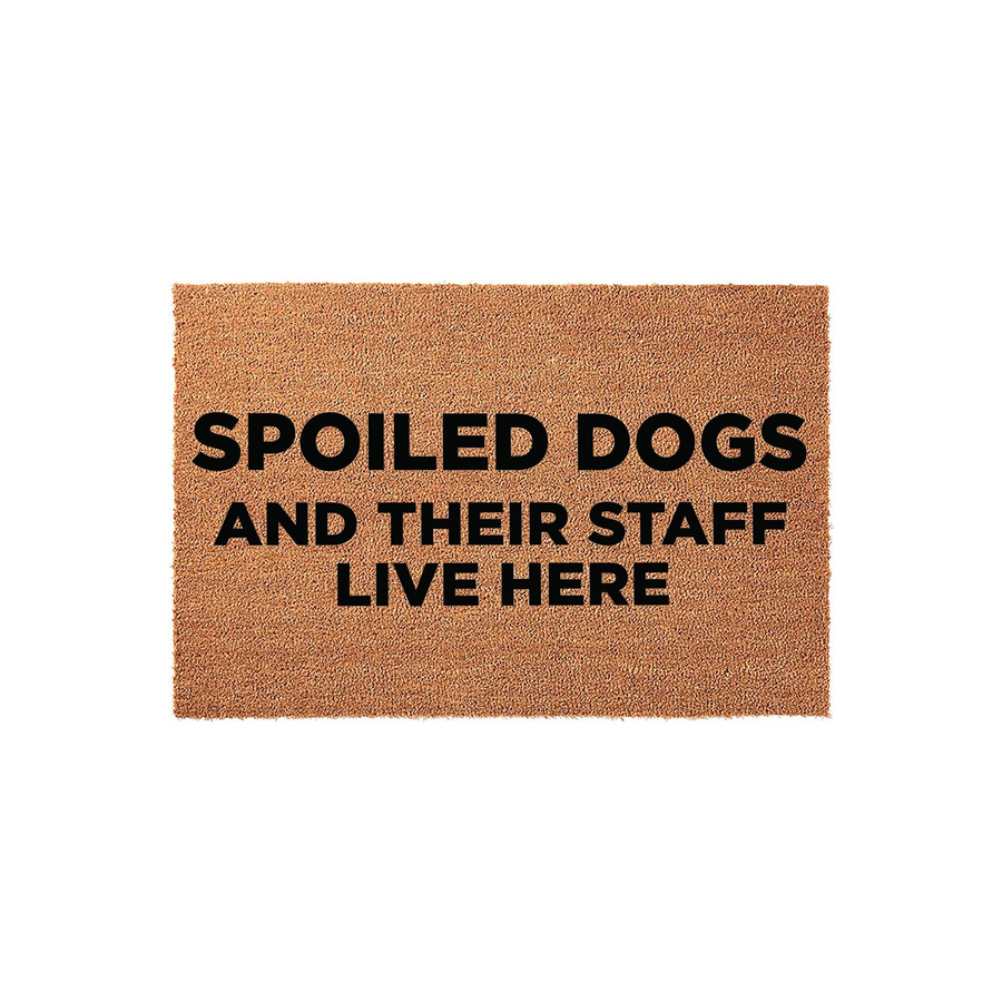 Spoiled Dogs and Their Staff Live Here coir doormat featuring a natural tan fiber texture and bold black lettering, providing a humorous and welcoming entrance for any pet-loving home with a durable, rustic outdoor design.