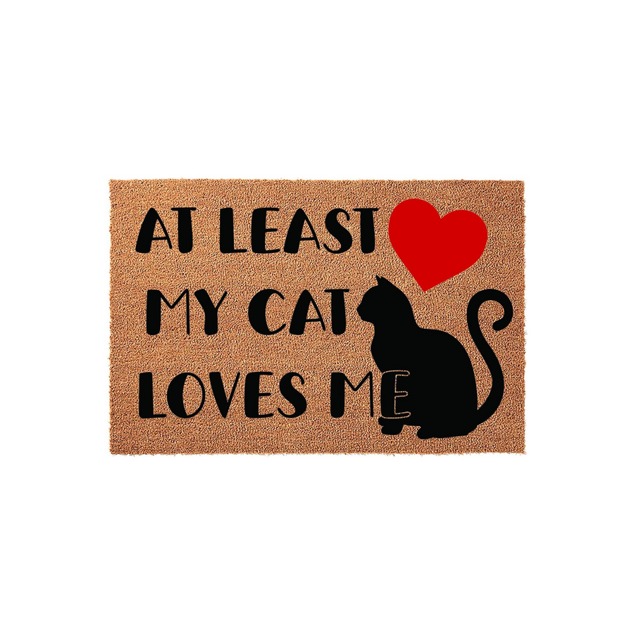At Least My Cat Loves Me coir doormat featuring a black cat silhouette and a bright red heart, designed with a humorous message for pet owners on a natural brown textured fiber surface against a clean white studio background.