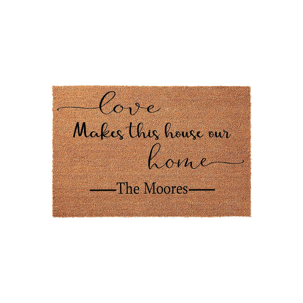 Personalized Family Name Coir Doormat featuring the phrase Love Makes this house our home in elegant black script and serif lettering, centered on a natural brown textured fiber mat for a welcoming front porch entrance decor.
