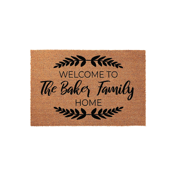 Personalized family name coir doormat featuring a rustic brown texture with black printed text that reads Welcome to the family home, accented by elegant leaf branch designs on a clean white studio background for a modern