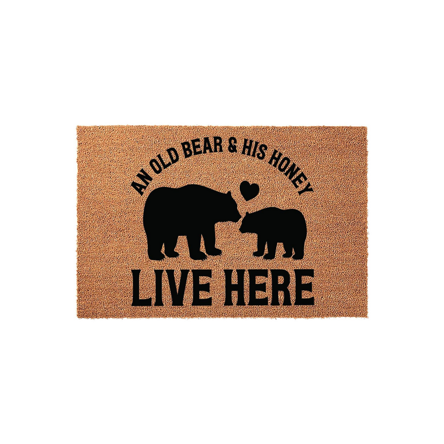 An Old Bear and His Honey Live Here doormat featuring a rustic coir texture with black printed silhouettes of two bears and a heart, creating a charming outdoor welcome mat for a couple who loves nature-inspired home decor.