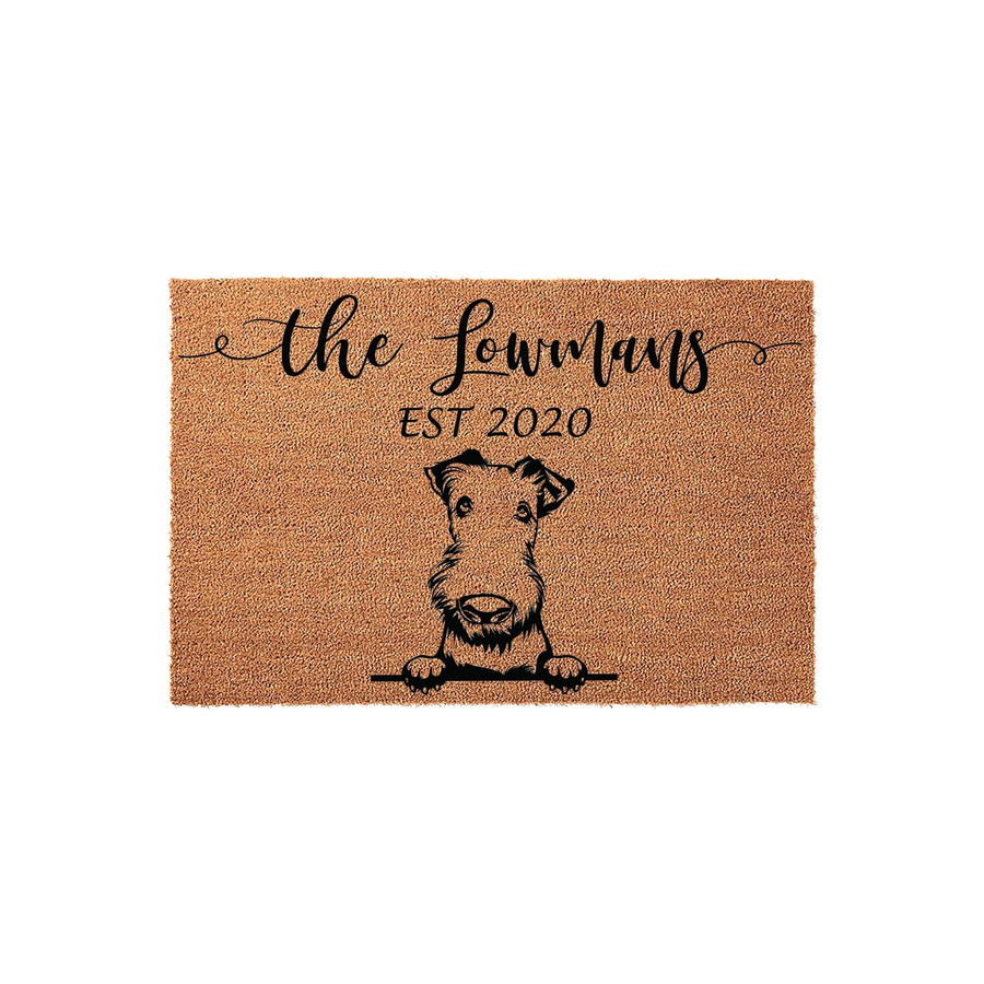 Personalized Airedale Terrier doormat featuring a cute dog illustration peeking over a line, with custom family name text and established year printed in black on a natural brown coir fiber mat for a welcoming front porch