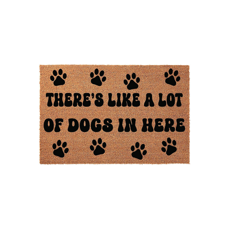 Funny Dog Lover Coir Doormat featuring the text There's Like A Lot Of Dogs In Here printed in bold black letters, surrounded by cute paw print icons on a natural tan fiber background for a charming entryway decor statement piece.
