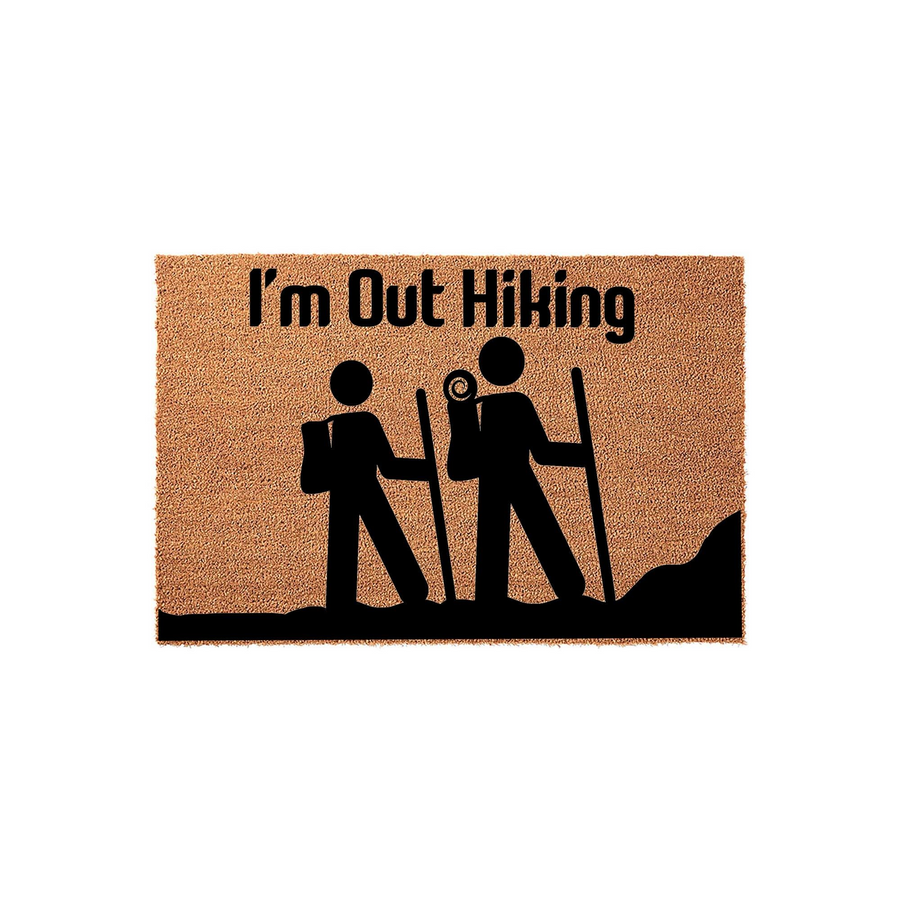 I'm Out Hiking coir doormat featuring a black silhouette graphic of two people with backpacks and walking sticks on a trail, set against a natural brown textured fiber background for a fun outdoor-themed entryway decor piece.