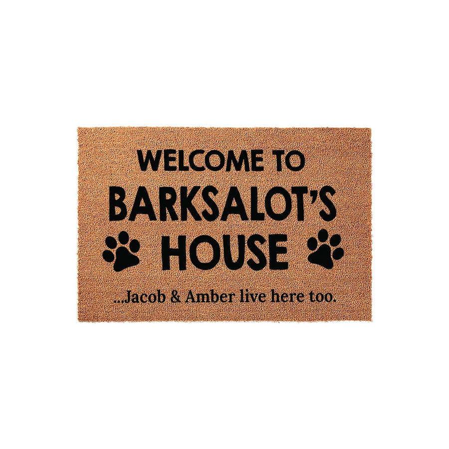 Personalized Dog Lover Coir Doormat featuring the text Welcome to Barksalot's House with black paw print icons and a secondary line noting that the humans live here too, set against a clean white background for a pet-friendly