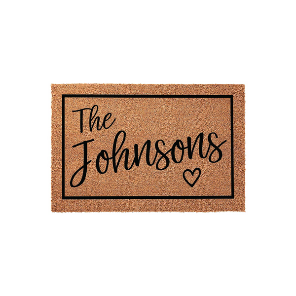 Personalized family name coir doormat featuring a black rectangular border and elegant script text that reads The Johnsons with a small heart icon, set against a clean white background for a modern home entryway decor style.