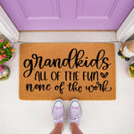 Grandkids all of the fun none of the work doormat, a natural coir fiber welcome mat for grandparents placed on a porch in front of a purple door, featuring stylish black script lettering and a heart icon for a fun home entryway
