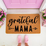 Grateful Mama coir doormat for front porch entry, featuring black script and block lettering on a natural fiber welcome mat, styled with pink sneakers and flowers at a bright pink door for a charming home decor entrance look.