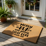 Mom life doormat with Messy Bun and getting stuff done text, a natural coir fiber welcome mat for front porch decor that features funny typography and arrow accents for a stylish home entrance and a humorous housewarming gift