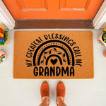Grandma doormat with a rainbow design and the text My Greatest Blessings Call Me Grandma, this natural fiber welcome mat is a stylish front porch decor piece for a home entrance, featuring a cute boho rainbow and heart