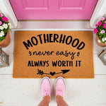 Motherhood doormat with a funny quote, this natural coir welcome mat features black text reading Motherhood never easy always worth it with an arrow and heart design, perfect for a front porch entryway or a housewarming home