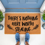 Funny doormat with the text There's Nothing Here Worth Stealing, a natural coir fiber welcome mat for front porch decor that makes a humorous housewarming gift for new homeowners looking for a unique and stylish entryway floor