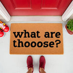 Funny what are thoose doormat featuring bold black text on a natural fiber coir welcome mat, placed outside a red front door with sneakers visible, making this a humorous entryway rug for home decor and housewarming gift ideas.