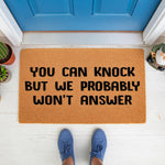 Funny doormat with the text You Can Knock But We Probably Won't Answer, a natural fiber welcome mat for front porch decor that makes a humorous housewarming gift for introverts who love sarcastic home entry floor mats.
