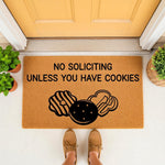 Funny No Soliciting Unless You Have Cookies doormat featuring black cookie illustrations on a natural coir welcome mat, placed on a front porch to create a humorous entryway decor piece for your home entrance and front door step.
