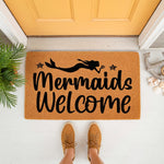 Mermaid welcome doormat featuring a black silhouette design on natural coir fiber, perfect for a beach house porch or coastal home decor, with starfish accents and a fun nautical theme for your front door entrance and entryway