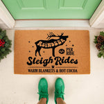 Reindeer Sleigh Rides Christmas doormat featuring a festive holiday design on natural coir fiber, perfect for a winter porch welcome mat, with seasonal pine and pinecone decor framing the entrance for a cozy holiday home look.