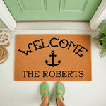 Personalized nautical welcome doormat with anchor design and custom family name, featuring a natural coir fiber texture on a front porch, perfect for coastal home decor, housewarming entry mats, and outdoor entryway floor mats.