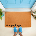 Funny Nice Package doormat for front porch entry, featuring a natural coir fiber welcome mat with bold black text, placed outside a bright blue door with a person wearing blue sneakers standing on the mat for a humorous home