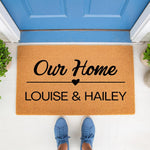 Personalized coir doormat for front porch entry featuring custom family names and a heart design, this natural fiber welcome mat creates a stylish home entrance decor piece for housewarming or wedding gifts on a bright white