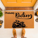 Probably Riding motorcycle doormat for bikers, featuring a black sport bike graphic on a natural coir welcome mat, placed on a porch floor for a fun outdoor entrance decor piece that shows off a passion for riding motorcycles.