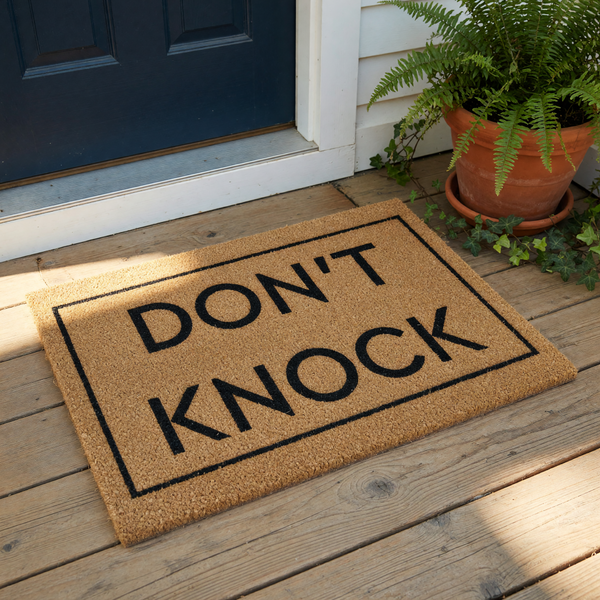 Don't Knock coir doormat with a bold black border and simple typography, perfect as a funny front porch welcome mat or housewarming entry rug for those who prefer privacy and quiet at their home entrance.
