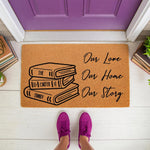 Personalized family name book stack doormat featuring a natural coir welcome mat design with Our Love Our Home Our Story text, perfect for a housewarming gift or front porch decor for book lovers and readers at their front door