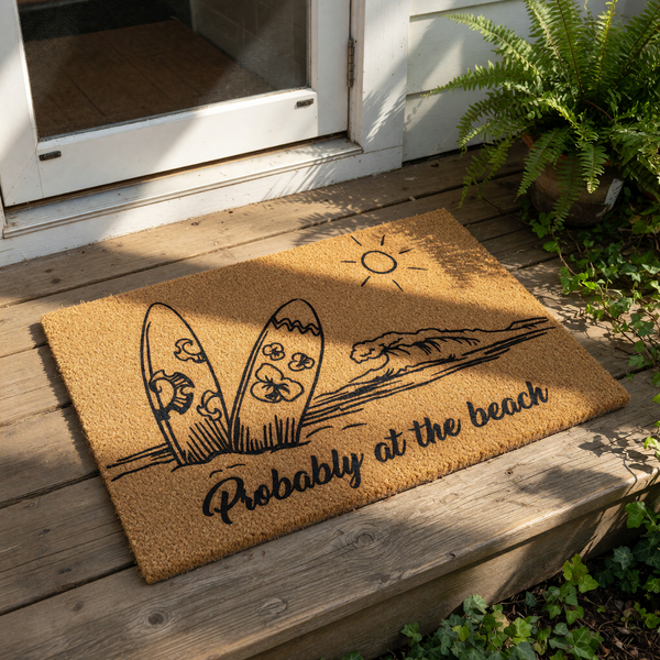 Probably at the beach coir doormat featuring a surf theme with surfboards, ocean waves, and a sun design, this natural fiber welcome mat is a stylish outdoor floor rug for coastal home decor and summer entryway floor mats.