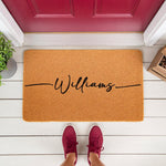 Personalized family name coir doormat featuring a custom last name in black script, displayed as a natural fiber welcome mat on a front porch, perfect for housewarming decor or a stylish entryway floor rug for your home entrance.