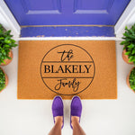 Personalized family name coir doormat featuring a circular design on a natural fiber welcome mat, perfect for front porch decor and housewarming entryways, shown with purple shoes on a clean outdoor floor mat for home entrance