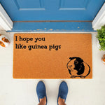 Guinea pig doormat with I hope you like guinea pigs text and a cute animal illustration, featuring a natural fiber welcome mat for pet lovers placed on a porch in front of a blue door for a fun and unique home entrance decor look.