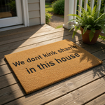 Funny doormat with the text We dont kink shame in this house printed on a natural coir fiber welcome mat, perfect for a front porch or entryway as a cheeky housewarming gift for friends with a bold sense of humor and home decor