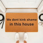 Funny kink shame doormat for front porch entry, featuring a natural coir welcome mat with bold black text, surrounded by leather whips and metal handcuffs, perfect for a cheeky home decor statement or a unique housewarming gift.