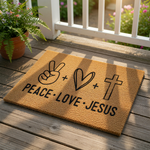 A doormat with the text "PEACE: LOVE: JESUS" printed on it, along with a peace sign and a cross.