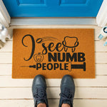 A wooden door mat with a humorous text that reads "I see NUMB PEOPLE".