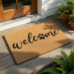 a welcoming mat with the word "welcome" written on it, placed on a tiled floor in front of a set of double doors.