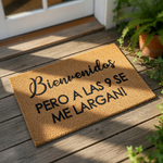 A welcome mat with the text "Bienvenidos PERO A LAS 9 SE ME LARGAN!" (Welcome to us, you are welcome!) written on it.