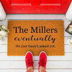 A rectangular, textured doormat with the text "The Millers eventually He just hasn't asked yet" printed on it.