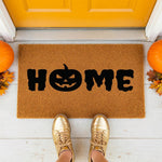 A door mat with the word "HOME" printed on it, surrounded by decorative elements such as a pumpkin and greenery.