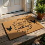A decorative door mat with the text "A whole new meaning to nesting" and silhouettes of chickens on either side.