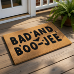 A textured door mat with the phrase "BAD AND BOO-JEE" printed on it.