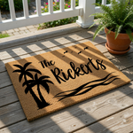 A decorative doormat with a palm tree and birds design, along with the text "The Rickerts" printed on it.