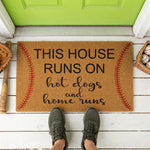 a door mat that says, this house runs on hot dogs and home runs