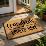A textured door mat with the phrase "Grandkids spoiled here" printed on it.