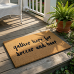 a textured area rug with the phrase "gather here for soccer and beer" printed on it.