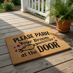 A textured door mat with the text "PLEASE PARK Your Broom at the DOOR" printed on it.