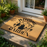A wooden door mat with the text "WELCOME TO MY GARDEN" printed on it, along with various gardening-related icons such as a watering can and a shovel.