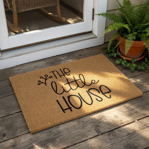 A textured doormat with the text "The little house" printed on it.