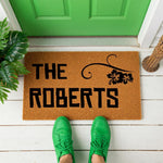 A wooden door mat with the name "The Roberts" printed on it.