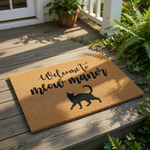A textured doormat with the phrase "Welcome to meow manor" printed on it, along with a silhouette of a cat.